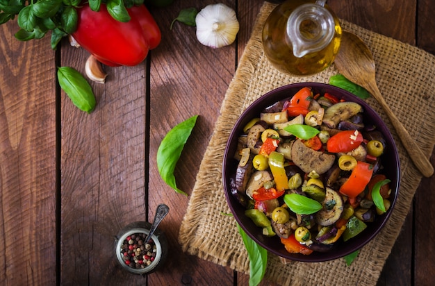 Hete pittige stoofpot aubergine, paprika, olijven en kappertjes met basilicum bladeren. Bovenaanzicht