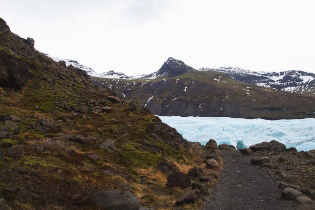 Heuvels bedekt met sneeuw en gras omgeven door een bevroren meer in Vatnajokull National Park