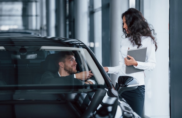 Hier zijn je sleutels. mannelijke klant en moderne zakenvrouw in de auto-sedan