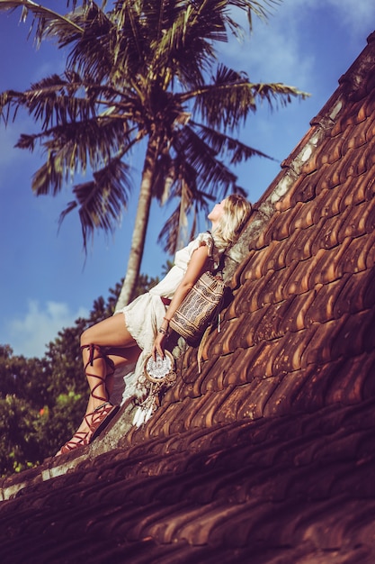 Gratis foto hippie meisje met lang blond haar in een jurk op het dak.