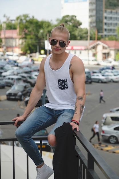 Gratis foto hipster knappe blonde man man in stijlvolle zomer kleding in de straat