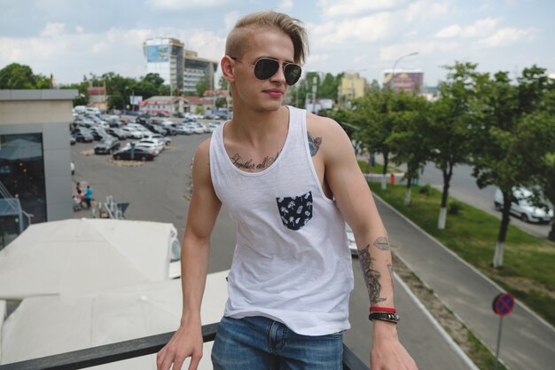 Hipster knappe blonde man man in stijlvolle zomer kleding in de straat