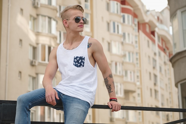 Hipster knappe blonde man man in stijlvolle zomer kleding in de straat