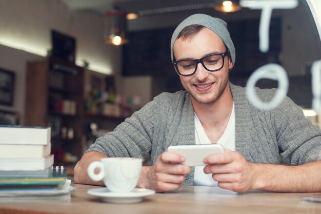 Hipster man met mobiele telefoon in café
