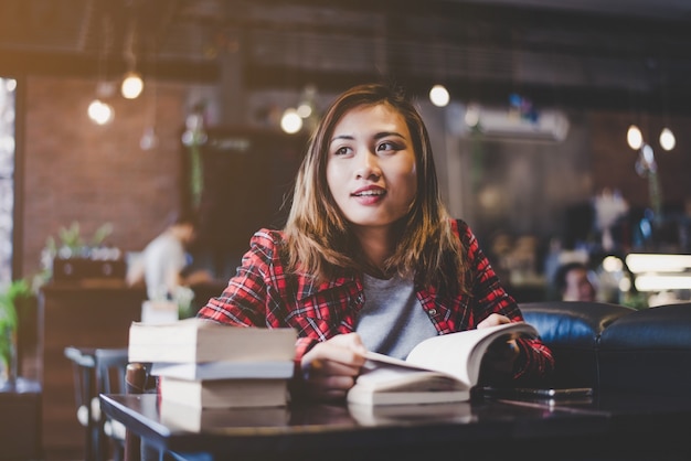 Hipster vrouw tiener zitten geniet van lezen boek op cafe. Vintage filter afgezwakt.