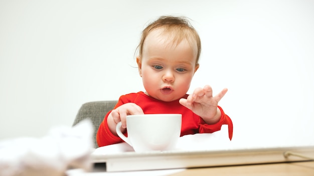 Hoe moe ik ben. kind babymeisje zit met toetsenbord van moderne computer of laptop in het wit