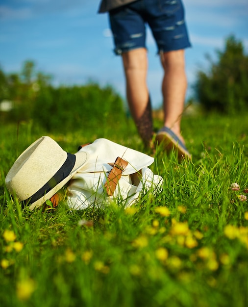 Hoed en zak die in het park in de zomer groen helder kleurrijk gras liggen