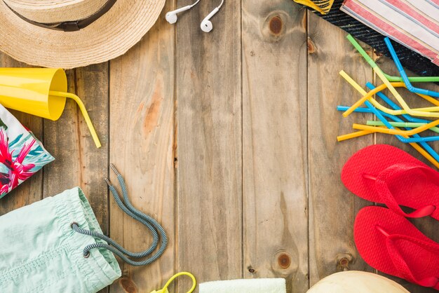 Hoed in de buurt van oortelefoons en flip-flops met beker en rietjes