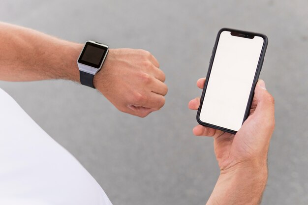 Hoge hoek atletische man met zijn telefoon met leeg scherm