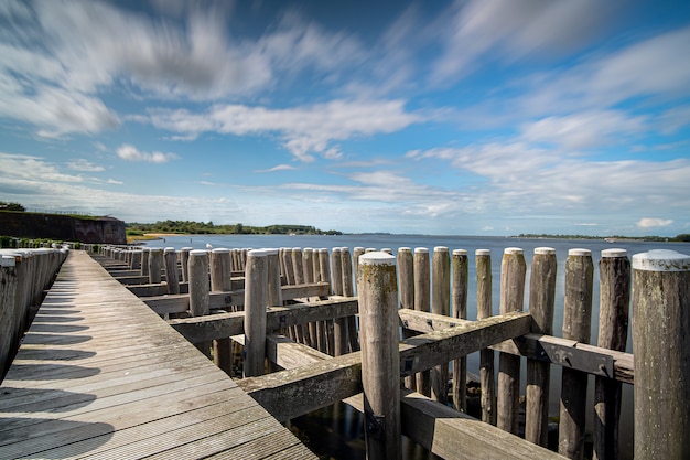 Gratis foto hoge hoek close-up shot van een houten hek aan de kust die leidt naar de zee