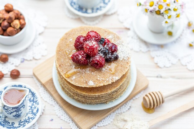 Hoge hoek close-up shot van rauwe veganistische pannenkoeken met honing en bessen