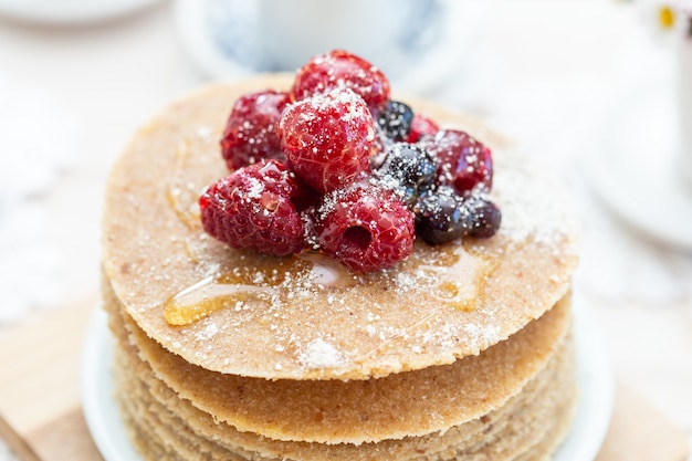 Hoge hoek close-up shot van rauwe veganistische pannenkoeken met honing en bessen