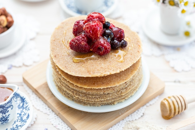 Hoge hoek close-up shot van rauwe veganistische pannenkoeken met honing en bessen