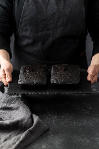 Hoge hoek die van banketbakker twee stukken van cake houdt