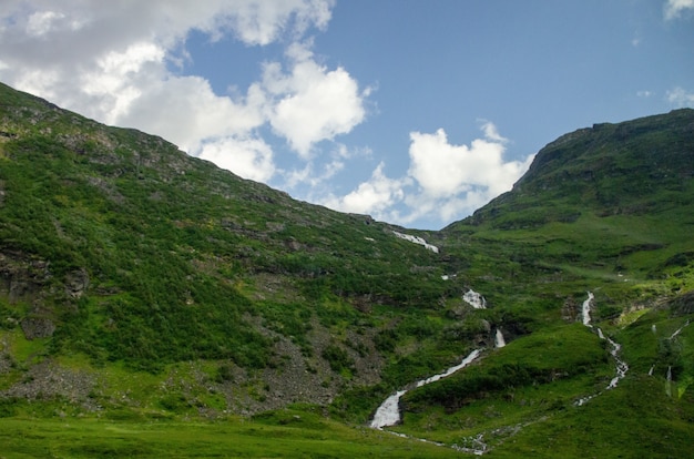 Hoge hoek die van een smalle sloot in de hoge groene bergen in Noorwegen is ontsproten