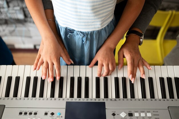 Hoge hoek jongen en leraar piano spelen