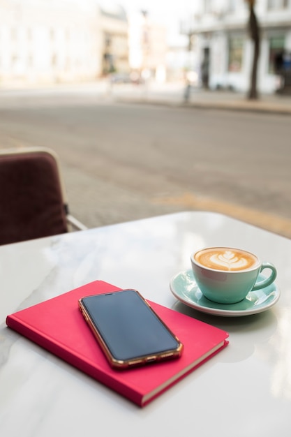 Gratis foto hoge hoek koffiekopje en smartphone op terras