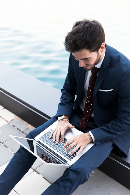 Hoge hoek man aan het werk op laptop in de buurt van het meer