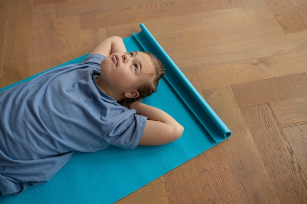 Hoge hoek meisje zittend op yoga mat