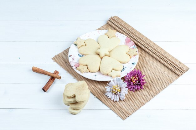 Gratis foto hoge hoek mening hartvormig en ster cookies, bloemen in placemat met kaneel