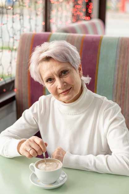 Hoge hoek oudere vrouw die van kop van koffie geniet