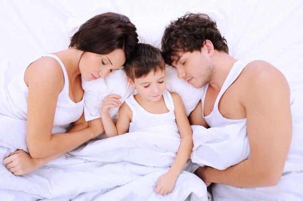 Hoge hoek portret van de slapende ouders met kleine jongen liggend op een bed