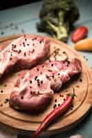 Gratis foto hoge hoek ruwe lapjes vlees op houten raad met peper en broccoli