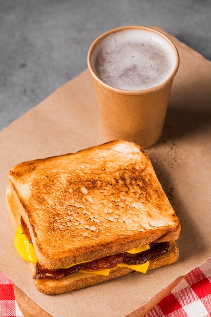 Hoge hoek sandwich met spek en kaas met koffie
