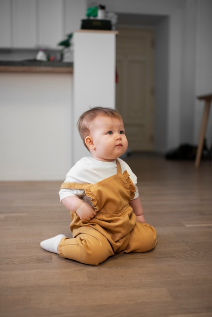 Hoge hoek schattige baby zittend op de vloer