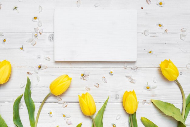 Hoge hoek shot van een blanco papier met gele tulpen op een witte tafel