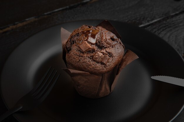 Hoge hoek shot van een chocolade muffin op een zwarte plaat op een donkere houten tafel