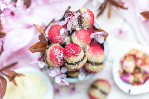 Hoge hoek shot van een kom met heerlijke veganistische perzik koekjes omgeven door kleine bloemen