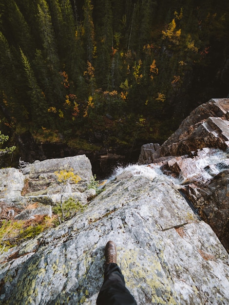 Hoge hoek shot van een persoon die op een rots bovenop een waterval in Noorwegen staat