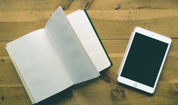 Hoge hoek shot van een tablet en een lege notebook met kopie ruimte op een houten tafel