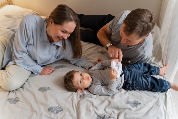 Hoge hoek smiley ouders en kind in bed