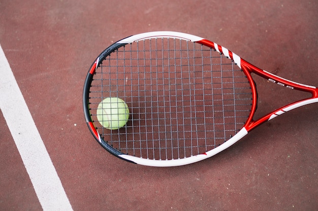 Hoge hoek tennisbal met racket naast