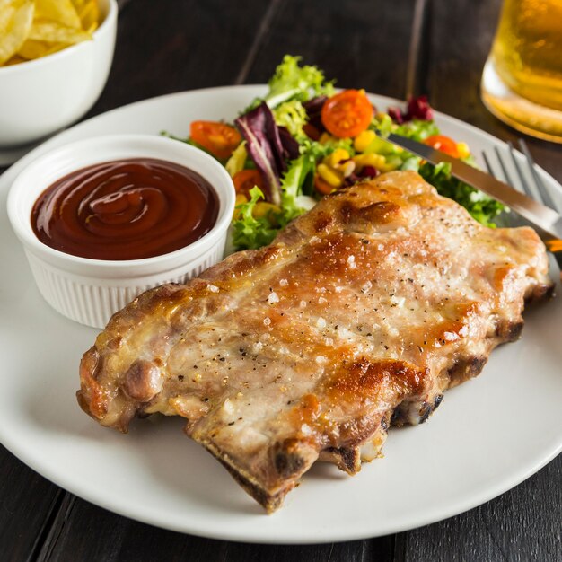 Hoge hoek van biefstuk op plaat met bier en saus