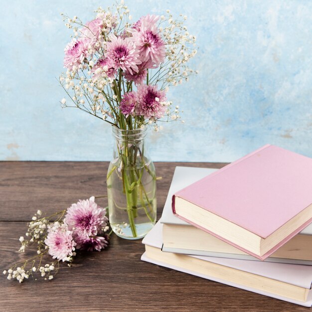 Hoge hoek van boeken en bloemen op houten tafel