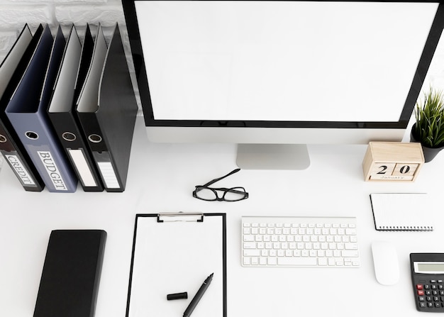 Hoge hoek van bureau met computerscherm en klembord