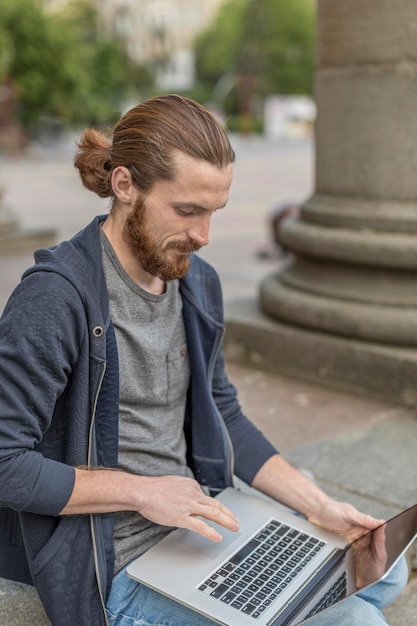 Hoge hoek van de mens die op laptop in de stad werkt