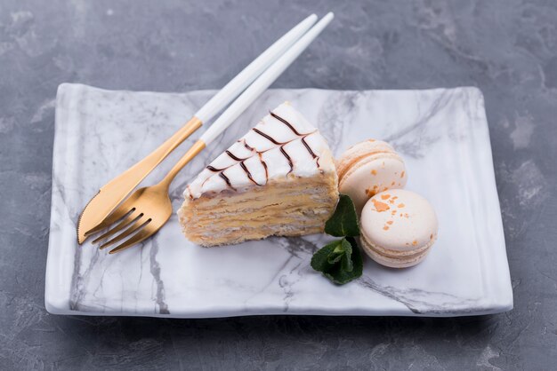 Hoge hoek van de taart op plaat met bestek en macarons