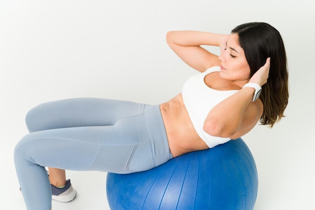 Hoge hoek van een jonge vrouw in sportieve kleding die sit-ups doet op een oefenbal. Actieve fitte vrouw die haar strakke buik uitoefent