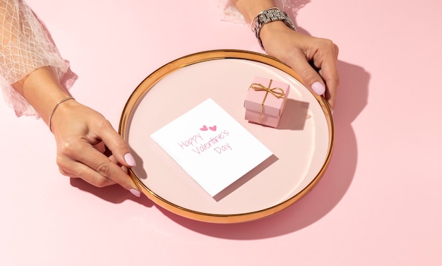 Gratis foto hoge hoek van een vrouw die een geschenkdoos op een bord aanbiedt voor valentijnsdag