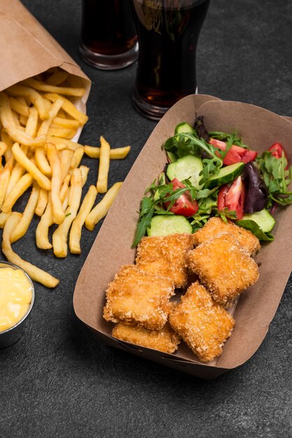 Hoge hoek van gebakken kipnuggets met frietjes en salade