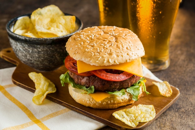 Hoge hoek van glazen bier met cheeseburger en chips