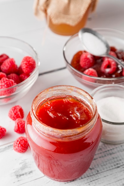 Hoge hoek van glazen pot met frambozenjam en fruit