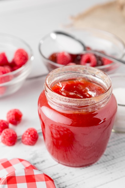 Hoge hoek van glazen pot met frambozenjam en fruit