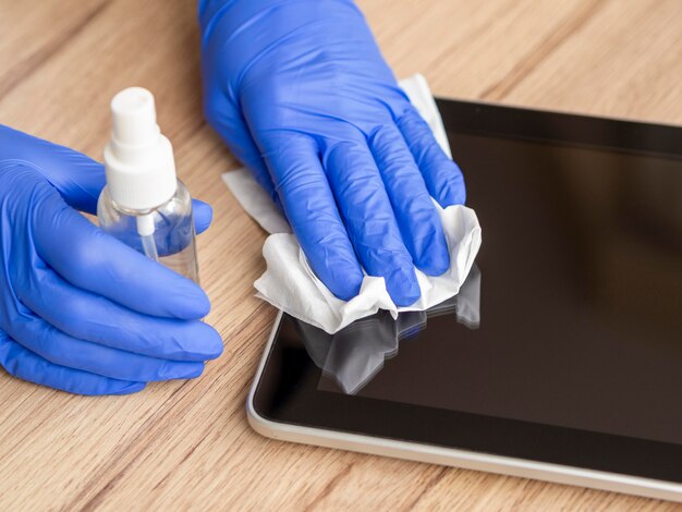 Hoge hoek van handen met chirurgische handschoenen desinfecterende tablet