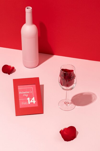 Hoge hoek van handen wijnfles met roos in glas en Valentijnsdag kaart