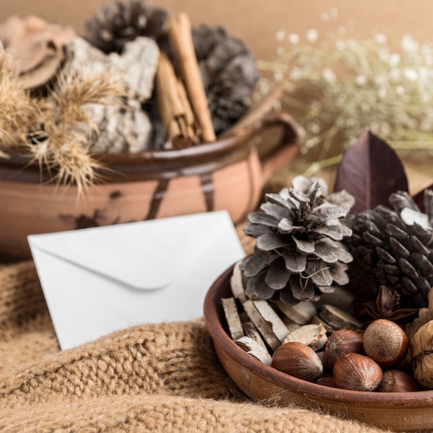 Hoge hoek van kom met dennenappels en envelop op jute